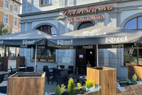 Zewnętrzny ogródek restauracji "Dolnośląska" z parasolami Kozel i stolikami.