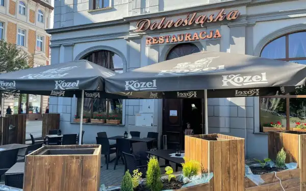 Zewnętrzny ogródek restauracji "Dolnośląska" z parasolami Kozel i stolikami.